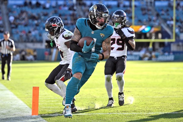 Jacksonville Jaguars wide receiver Parker Washington (11) scores ahead of Houston Texans cornerback Kamari Lassiter (4) and safety M.J. Stewart (29) during the second half of an NFL football game Sunday, Dec. 1, 2024, in Jacksonville, Fla. (AP Photo/Phelan M. Ebenhack)