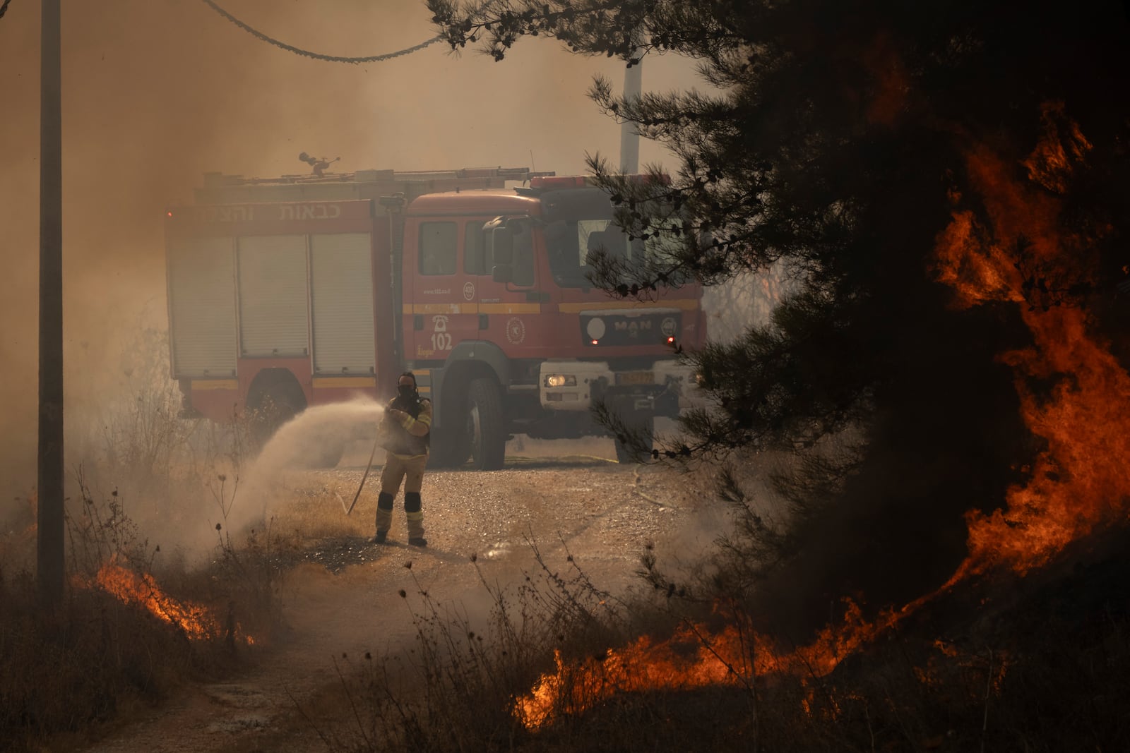 A firefighter works to extinguish a fire after a rocket, fired from Lebanon, hit an area near the town of Rosh Pinna, northern Israel, Sunday, Oct. 20, 2024. (AP Photo/Leo Correa)