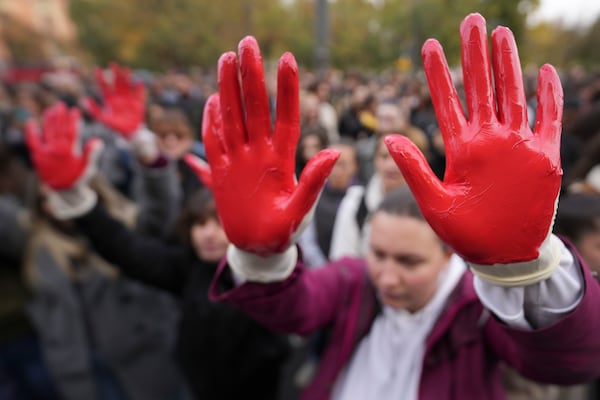 Protesters shout slogans with red paint on the hands symbolizing blood, demand arrests, two days after a concrete canopy collapsed at a railway station in Novi Sad, killing 14 people and injuring three, during protest in Belgrade, Serbia, Sunday, Nov. 3, 2024. (AP Photo/Darko Vojinovic)