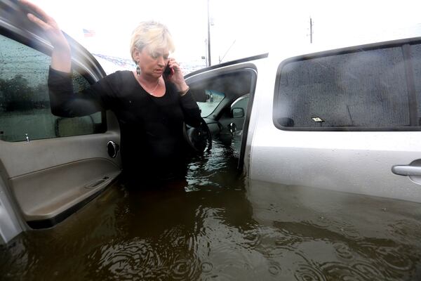 Rhonda Worthington talks on her cell phone with a 911 dispatcher after her car became stuck in rising floodwaters from Tropical Storm Harvey in Houston, Texas, Monday, Aug. 28, 2017. Worthington said she thought the water was low enough to drive through before the vehicle started to float away. (AP Photo/LM Otero)