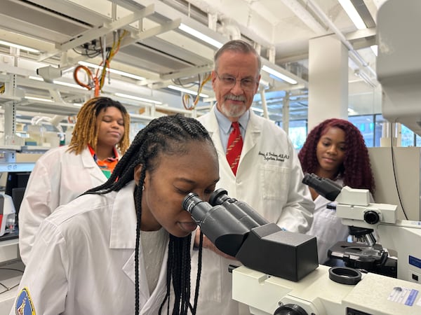 In this file photo, Dr. Barney Graham watches with Morehouse School of Medicine students Briana Brock, left and Dana Battle, right, as a Morehouse School of Medicine student looks into a microscope .