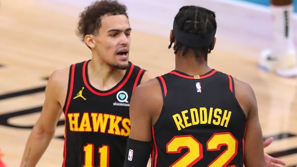 Hawks guard Trae Young (left) confers with teammate Cam Reddish as he returns to action against the Milwaukee Bucks during the second quarter of Game 2 in the Eastern Conference finals Friday, June 25, 2021, in Milwaukee. (Curtis Compton / Curtis.Compton@ajc.com)