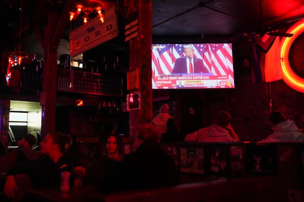 People watch as television screens show Republican presidential nominee former President Donald Trump addressing supporters on Election Day, Tuesday, Nov. 5, 2024, at Comet Tavern in Seattle. (AP Photo/Lindsey Wasson)