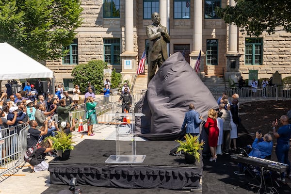 Dignitaries pull the cover off the statue during the unveiling ceremony honoring the late Congressman John Lewis in Decatur on Saturday, Aug 24, 2024.  (Steve Schaefer / AJC)