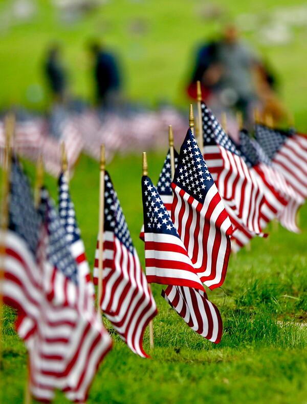 Staff and day program participants from Pittsburgh Mercy Intellectual Disabilities Services place flags on the graves of veterans at the Allegheny Cemetery in Pittsburgh, Wednesday, May 23, 2018, for the upcoming Memorial Day holiday weekend. (AP Photo/Keith Srakocic)