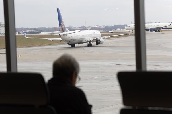   Travelers sit and watch jets depart in the new Concourse T extension at Hartsfield-Jackson Atlanta International Airport Tuesday, December 13, 2022.    (Steve Schaefer/steve.schaefer@ajc.com)