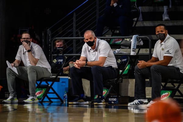 Georgia Tech assistant coach Eric Reveno (center) on the bench for the Yellow Jackets' win over Florida State on Jan. 30, 2021. He is sitting between assistant coach Anthony WIlkins (to Reveno's left) and director of operations Tyler Benson (to his right). (Danny Karnik/Georgia Tech Athletics)