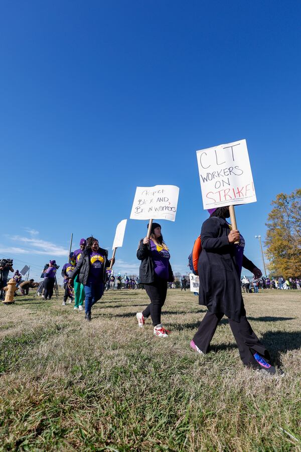 Airport workers wave signs as they march in front of the Charlotte Douglas International Airport in Charlotte, N.C., Monday, Nov. 25, 2024. (AP Photo/Nell Redmond)