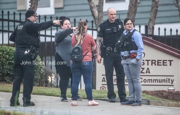 Atlanta police officers speak with citizens outside the Martin Street Plaza Apartments after an officer-involved shooting Monday morning.