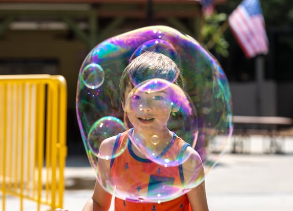 Kincaid Wright, 7, looks through bubbles within bubbles created by Booth. (Arvin Temkar / arvin.temkar@ajc.com)