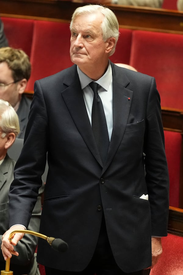 French Prime Minister Michel Barnier holds a microphone h at the National Assembly while France's minority government may be on its last legs as opposition lawmakers moved this week toward a no-confidence vote, Monday, Dec. 2, 2024 in Paris. (AP Photo/Michel Euler)