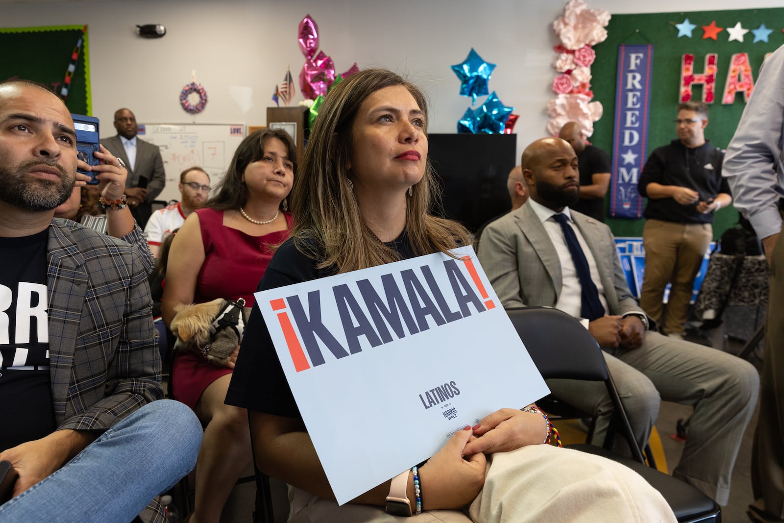 Volunteer Luisa Cardona holds a campaign sign while attending a press conference at a Democratic campaign office in Norcross on Tuesday, October 29, 2024. Local Puerto Rican leaders were invited to speak after a comedian at a rally or Republican presidential candidate Donald Trump called Puerto Rico a “floating island of garbage.” (Arvin Temkar / AJC)