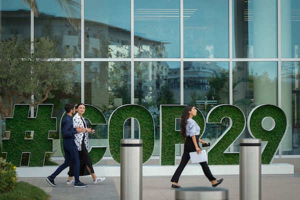 People walk by a sign for COP29, the United Nations Climate Change Conference, in Baku, Azerbaijan, Tuesday, Sept. 17, 2024. (AP Photo/Sergei Grits)