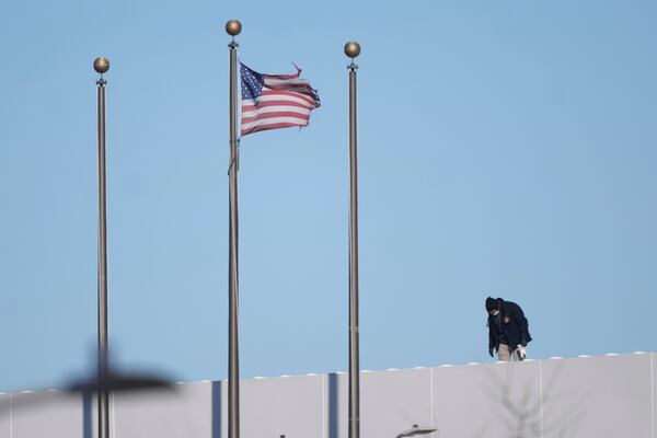 An investigator looks around the roof of a department store near the scene where a small plane crashed in Philadelphia, Saturday, Feb. 1, 2025. (AP Photo/Matt Rourke)