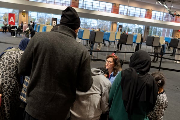 An election official helps check in voters at Ford Community and Performing Arts Center on the last day of early in-person voting, Sunday, Nov. 3, 2024, in Dearborn, Mich., the nation's largest Arab-majority city. (AP Photo/David Goldman)