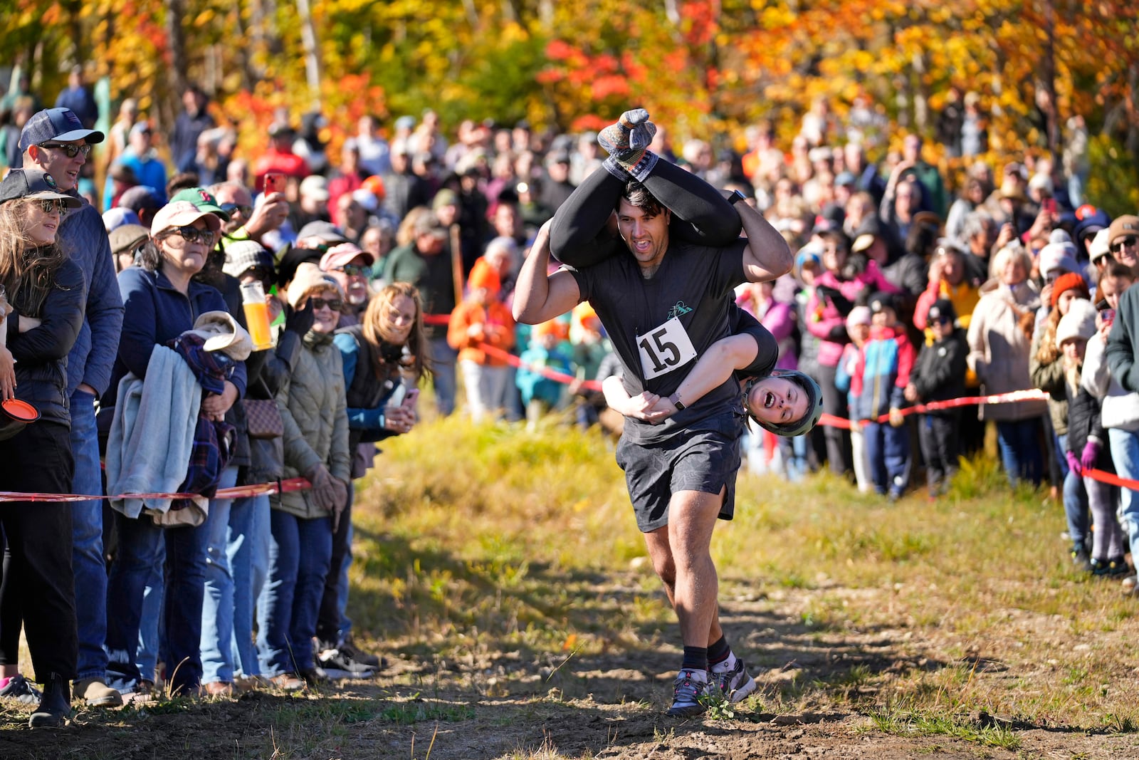 Nic Vinsonhaler carries Tara Rogowski while competing in the North American Wife Carrying Championship, Saturday, Oct. 12, 2024, at Sunday River ski resort in Newry, Maine. (AP Photo/Robert F. Bukaty)