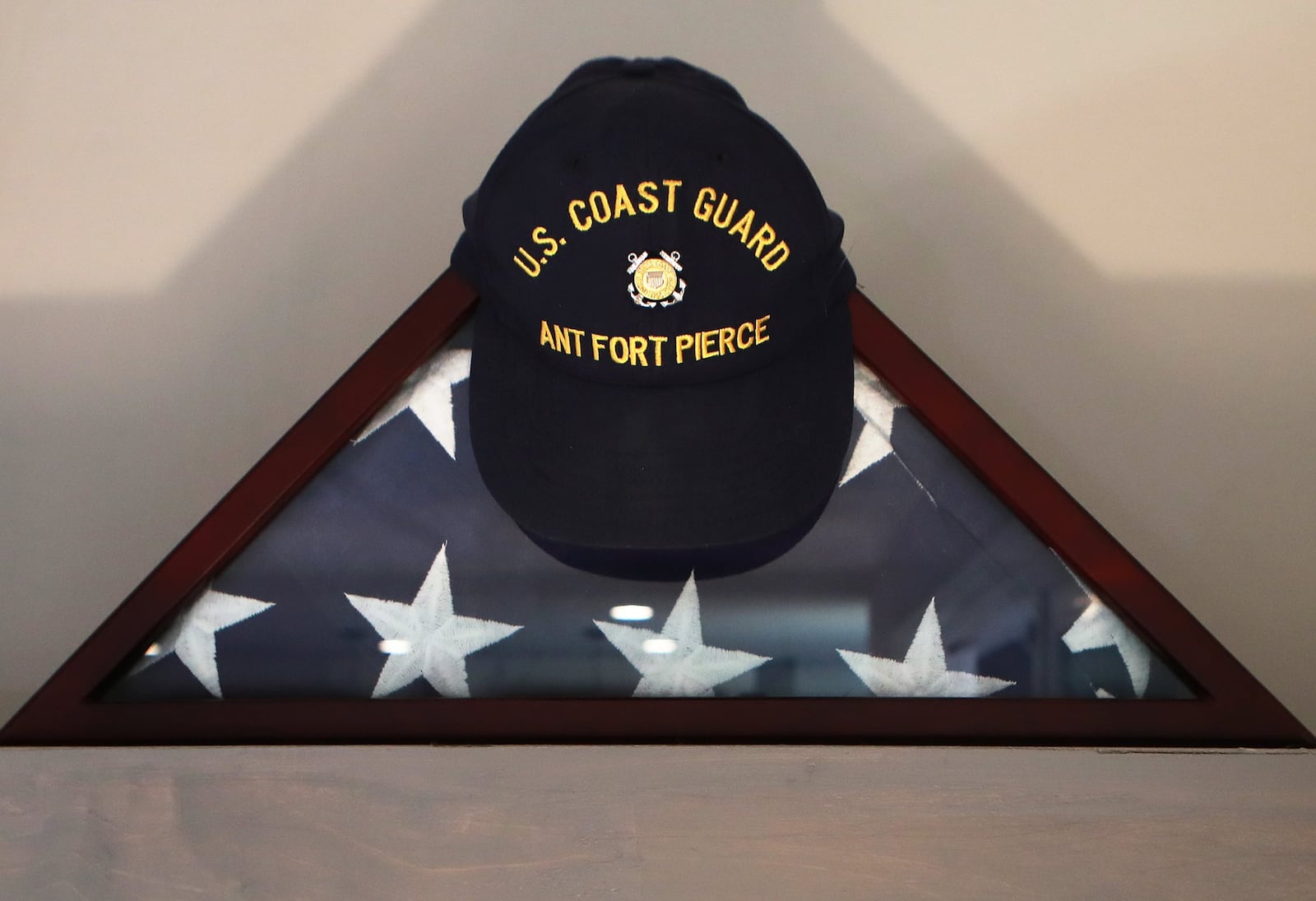 A U.S. flag and hat from Kaitlin Hunt’s U.S. Coast Guard unit sit on a shelf in the home of her dad and stepfather. Curtis Compton/ccompton@ajc.com