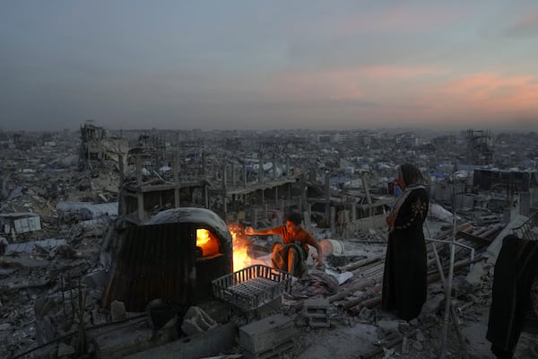 Palestinians Ali Marouf and his mother Aisha cook on fire on the roof of their destroyed house by the Israeli army's air and ground offensive in Jabaliya, Gaza Strip, on Monday, March 17, 2025. (AP Photo/Jehad Alshrafi)