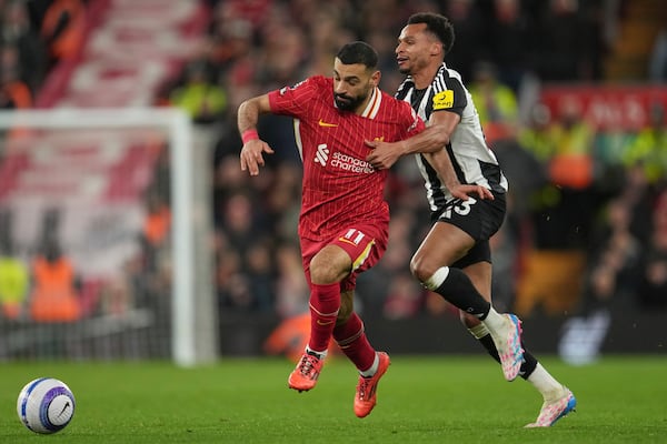 Newcastle's Jacob Murphy, right, challenges Liverpool's Mohamed Salah during the English Premier League soccer match between Liverpool and Newcastle United at Anfield in Liverpool, Wednesday, Feb. 26, 2025. (AP Photo/Jon Super)