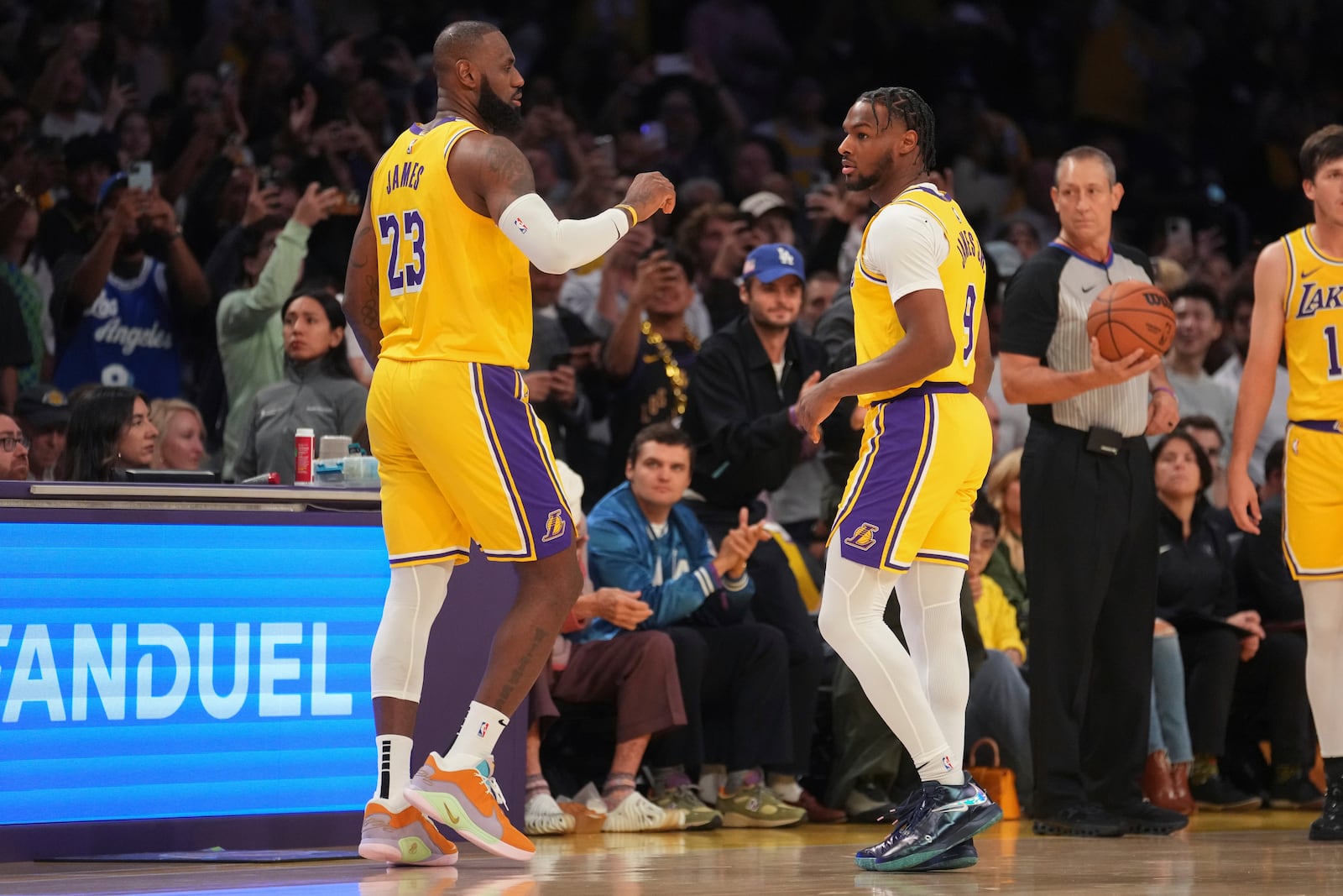 Los Angeles Lakers forward LeBron James (23) and guard Bronny James (9) stand on the court during the first half of an NBA basketball game against the Minnesota Timberwolves, Tuesday, Oct. 22, 2024, in Los Angeles. (AP Photo/Eric Thayer)