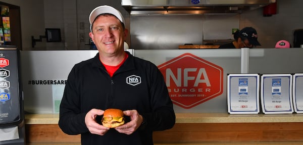 230217 Dunwoody, Ga: NFA Burger owner Billy Kramer with one of his signature burgers at his burger bar located in a Chevron gas station/convenience store in Dunwoody, Ga. Photos for Culinary Journey series on Billy Kramer, owner and originator of NFA Burger in Dunwoody, Georgia. The unique and critically acclaimed burger stand that started (in 2019) and remains in a gas station in the northern suburbs of Atlanta, Ga. is a go-to destination for many foodies pursuing the best burger available, still at a reasonable price. Photos taken Friday February 17, 2023. 021823CULINARYJOURNEYNFABURGER (CHRIS HUNT FOR THE ATLANTA JOURNAL-CONSTITUTION)