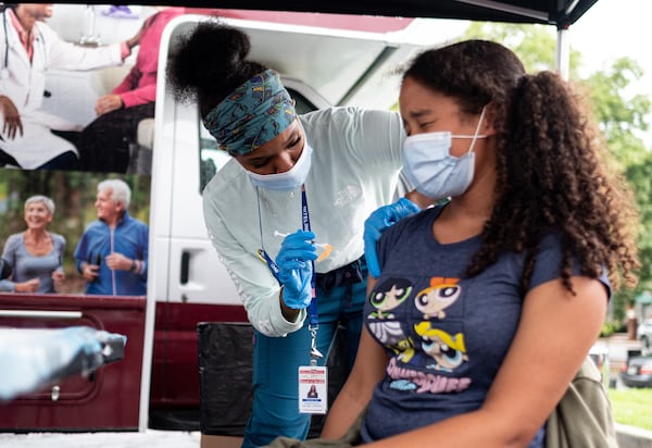 Ashanti Booker, a registered nurse with the DeKalb County Board of Health, gives a Covid-19 vaccination to Raya High, 13, at a mobile clinic at Decatur High School on Monday afternoon, July 19, 2021. Ben Gray for the Atlanta Journal-Constitution