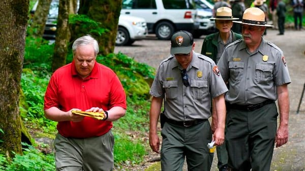 This Wednesday, May 6, 2020 image from a tweet by Interior Secretary David Bernhardt, the Interior Secretary visits with National Parks Service employees at Great Smoky Mountains National Park. While the Interior Secretary asked visitors to social distance when the park reopens on May 9, neither Bernhardt nor park staff wore face masks in the photos, as they talked and walked inches apart during his visit on Tuesday, May 5.  (National Parks Service via AP)