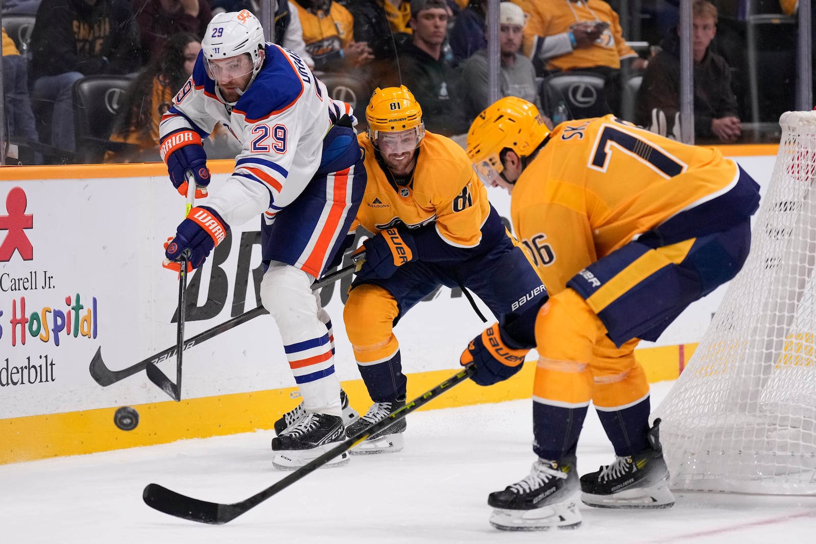 Edmonton Oilers center Leon Draisaitl (29) passes the puck past Nashville Predators center Jonathan Marchessault (81) and defenseman Brady Skjei (76) during the third period of an NHL hockey game Thursday, Oct. 17, 2024, in Nashville, Tenn. (AP Photo/George Walker IV)