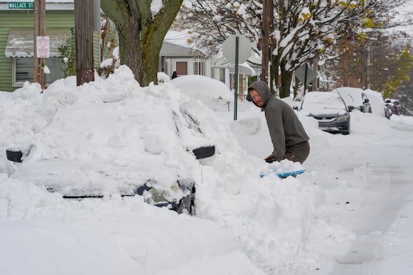 Matthew Jewell shovels snow off his father's car on a side street in Erie, Pa., Monday, Dec 2, 2024. AP Photo/Gene J. Puskar)