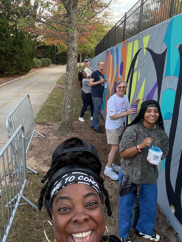 Vera Ziegler, front, with volunteers painting the community mural.