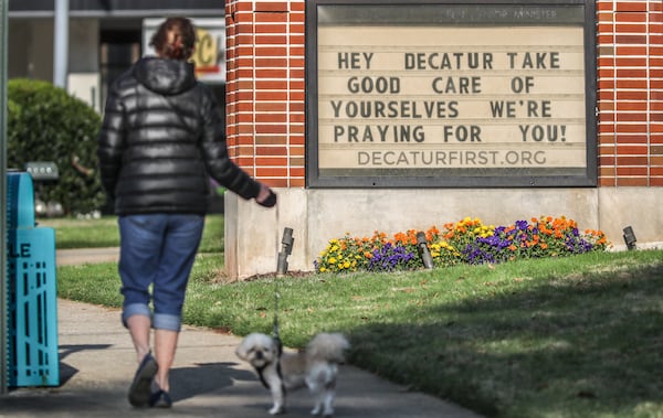 In this late March file photo, Marcia Soldat walks her dog, Duke, past a sign offering prayer support to the community posted in front of Decatur First United Methodist Church, 300 East Ponce de Leon Ave. JOHN SPINK/JSPINK@AJC.COM