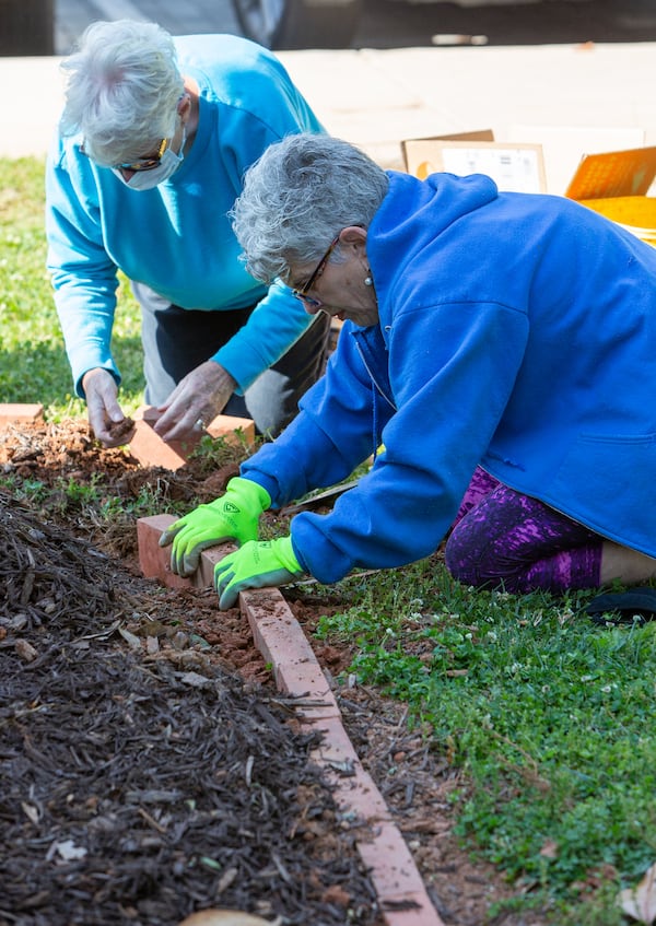 Peggy Burgess (left) and Kerry Quinn work on a brick border in new garden area in front of Avondale Elementary School features hand painted totem poles and a lending library. The Avondale Estates Garden Club and the Avon Garden Club worked together on the project.
PHIL SKINNER FOR THE ATLANTA JOURNAL-CONSTITUTION.