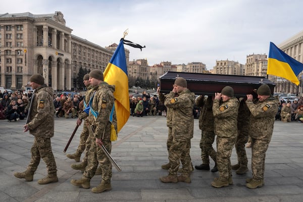 People kneel down as Ukrainian servicemen carry the coffin of their fellow-soldier Vasyl Ratushnyy, 28 during the funeral ceremony in the Independence square in Kyiv, Ukraine, Wednesday, March 5, 2025. (AP Photo/Efrem Lukatsky)