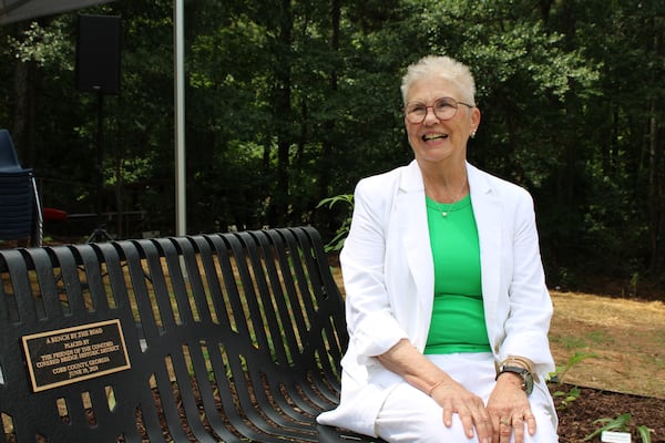 Pat Burns, who spearheaded the bench project to honor former slave Matilda Ruff and her children, sits atop the bench at its unveiling on Tuesday, June 18, 2024. “There are plaques up about the Ruff family and the Ruff houses and the Ruff mills, but there was nothing to recognize Matilda and her children,” Burns said. (Taylor Croft/taylor.croft@ajc.com)