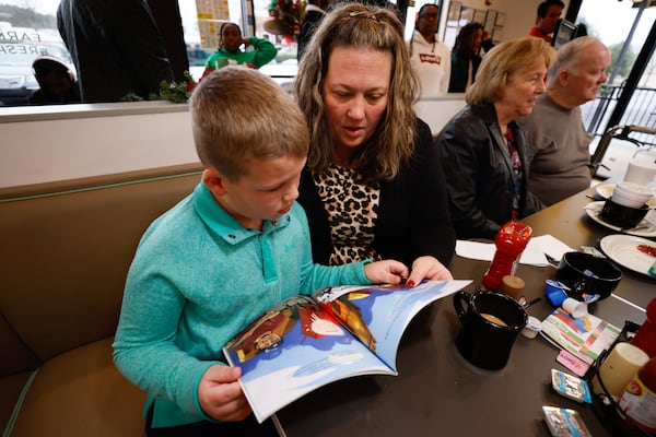 Brandee Hanes reads a book with her son Owen at Eggs Up Grill in Morrow on Sunday, Dec. 17, 2023. The Read in Color program provides books for patrons while they wait to eat or when they leave. (Miguel Martinez / miguel.martinezjimenez@ajc.com)