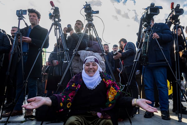 A Kurdish woman gestures as she waits to watch live on a tv screen a Pro-Kurdish Peoples' Equality and Democracy Party, or DEM, delegation members releasing an statement from the jailed leader of the rebel Kurdistan Workers' Party, or PKK, Abdullah Ocalan, in Diyarbakir, Turkey, Thursday, Feb. 27, 2025. (AP Photo/Metin Yoksu)