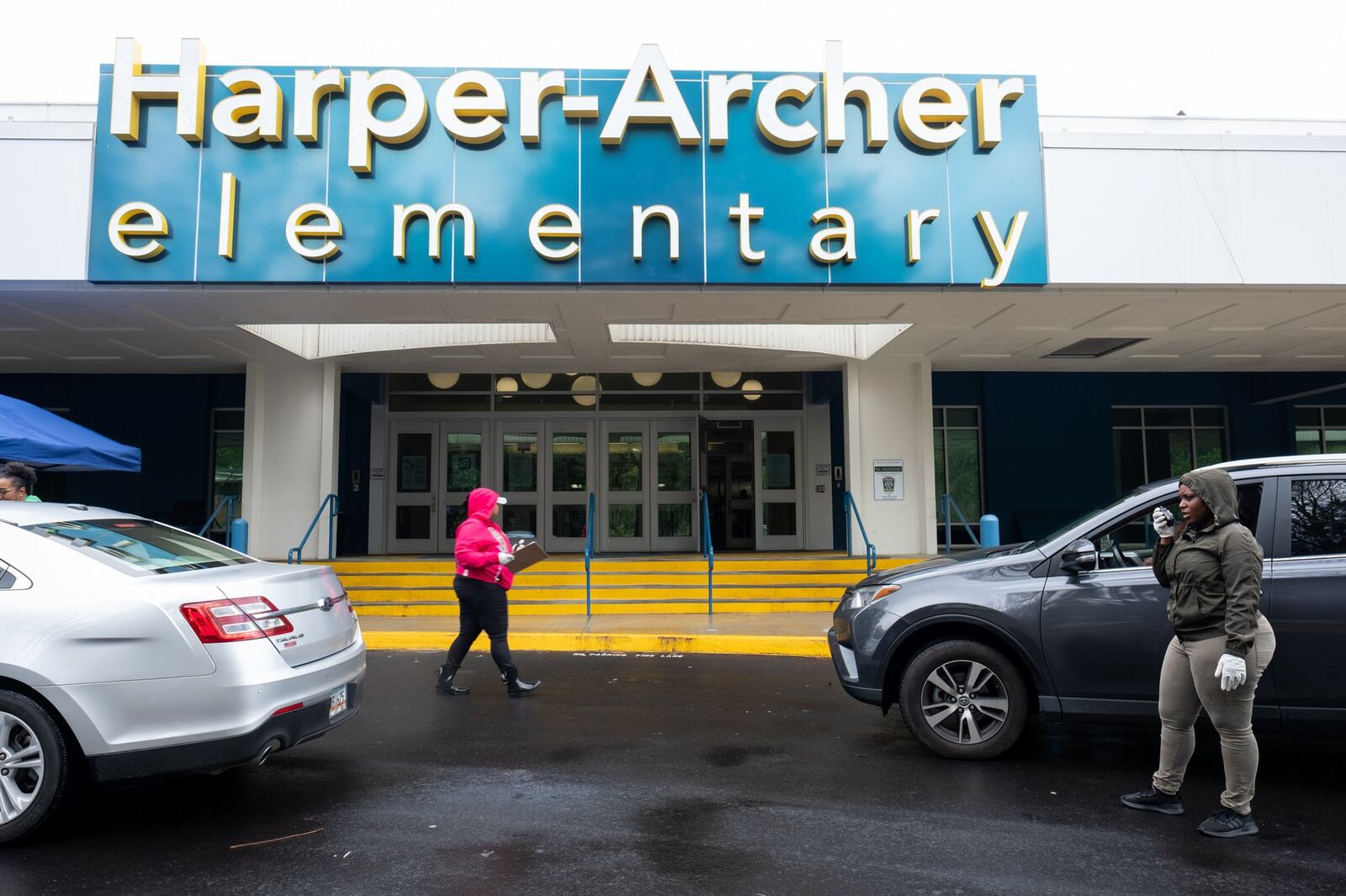 Kydeia Mahaffey-Jones, left, and Diamond Parks, both paraprofessionals at Harper-Archer Elementary School, distribute devices to parents who drove up to the school on March 24, 2020. The school was issuing devices to students so they could continue studying during the coronavirus pandemic. Ben@BenGray.com for the Atlanta Journal-Constitution