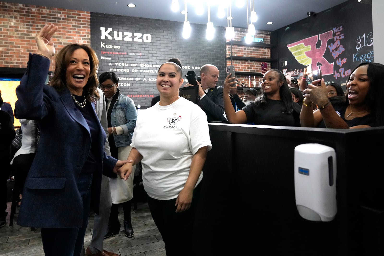 Democratic presidential nominee Vice President Kamala Harris, from left, greets a member of the restaurant staff during a campaign stop at Kuzzo's Chicken and Waffles in Detroit, Sunday, Nov. 3, 2024. (AP Photo/Jacquelyn Martin)