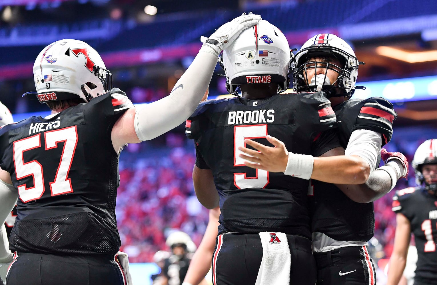 North Oconee teammates Nate Hiers (57) and Patrick Elliott (11) celebrate with Khamari Brooks (5) after Brooks scored the Titans’ first touchdown against Marist during the first half of a Class 4A championship game at the Mercedes-Benz Stadium Monday, Dec. 16, 2024. (Photo/Daniel Varnado)