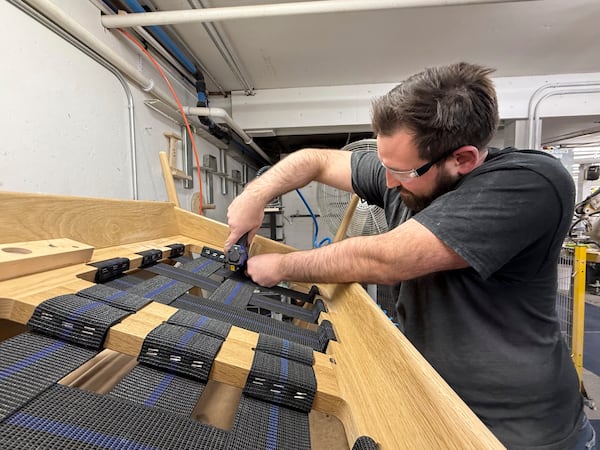 Built by Newport furniture company employee Eric Benware puts webbing on a sofa after the business's owner Dave Laforce, who sources material from Canada, attended a roundtable event with U.S. Sen. Peter Welch of Vermont and Marie-Claude Bibeau, a Canadian member of parliament, to discuss the Trump administration's tariffs, Tuesday, March 18, 2025, in Newport, Vt. (AP Photo/Amanda Swinhart)