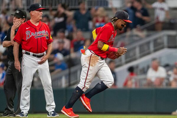 Atlanta Braves manager Brian Snitker tells right fielder Ronald Acuna Jr. to change his glove during the ninth inning of the team's baseball game against the San Francisco Giants, Friday, Aug. 18, 2023, in Atlanta. (AP Photo/Hakim Wright Sr.)