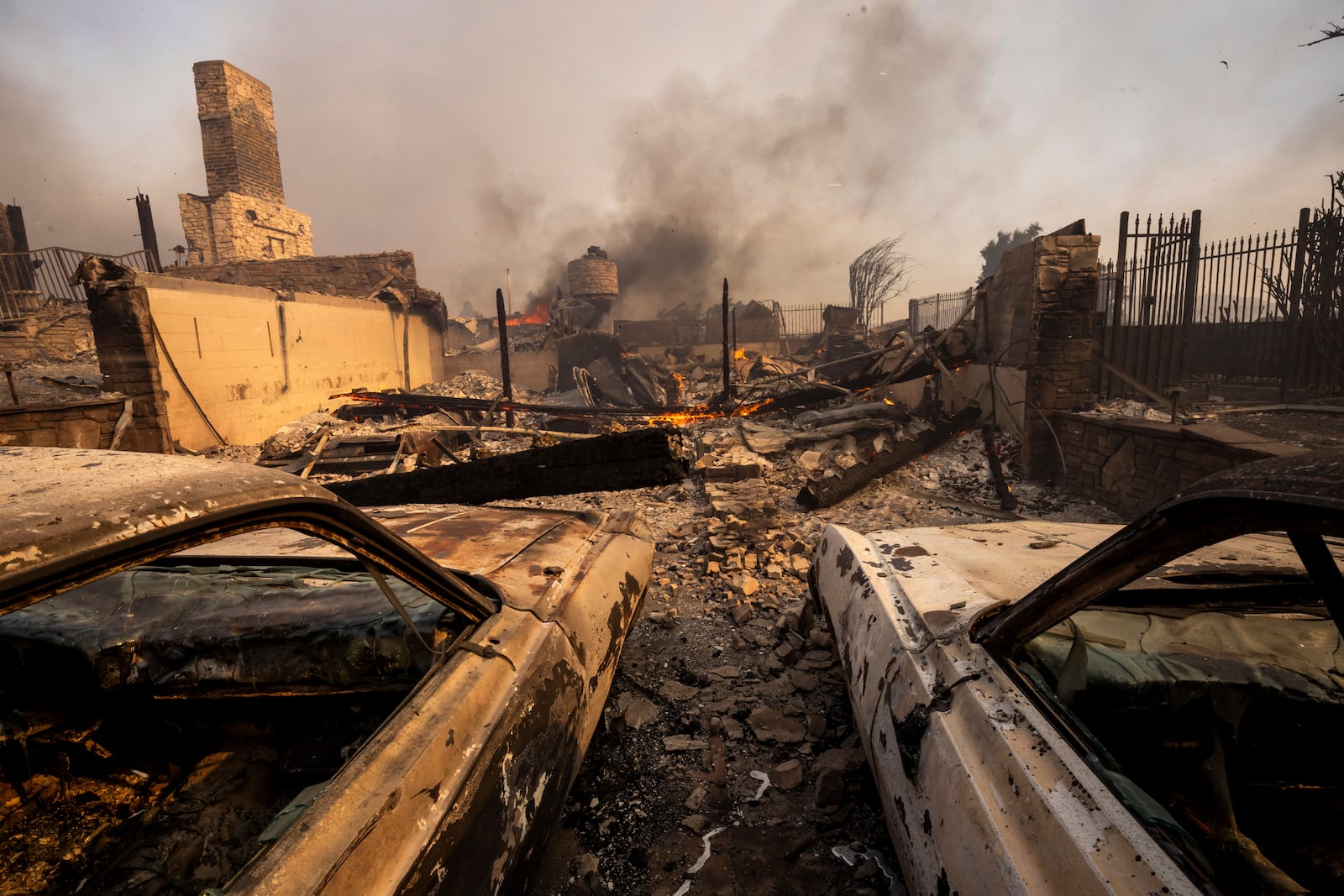 Burned vehicles sit among a destroyed home in the Mountain fire, Wednesday, Nov. 6, 2024, near Camarillo, Calif. (AP Photo/Ethan Swope)