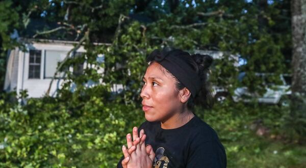 Alicia Verdugo stands outside her family's crushed Grand Avenue home Thursday morning in southwest Atlanta, surveying the damage after a tree fell during strong storms the night before.