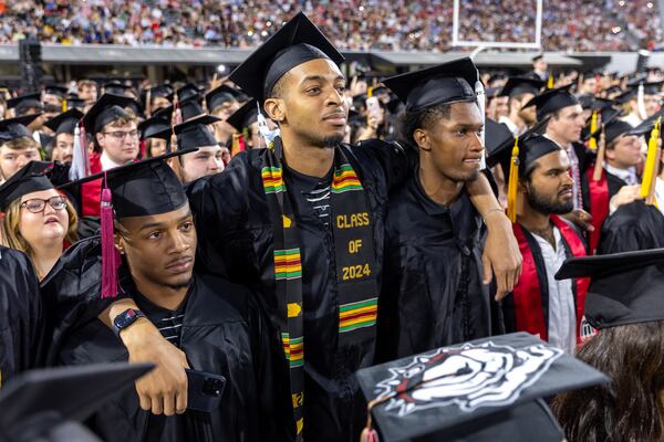 Graduates listen to a singer sing Georgia on My Mind at Sanford Stadium during the University of Georgia spring commencement in Athens on Friday, May 10, 2024. (Arvin Temkar / AJC)