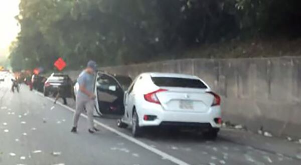 Video image shows drivers stopping to collect money that fell from an armored truck when its side door flew open on I-285. SOCIAL MEDIA POST