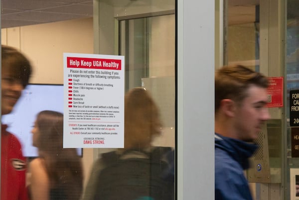 New residents of the Lipscomb dormitory exit the building past a sign advising persons experiencing COVID-19 symptoms not to enter on Monday, Aug. 16, 2021 on the University of Georgia's Campus in Athens, Georgia. The University does not have a mask or vaccine mandate, and is not requiring testing. (Julian Alexander for the Atlanta Journal-Constitution)