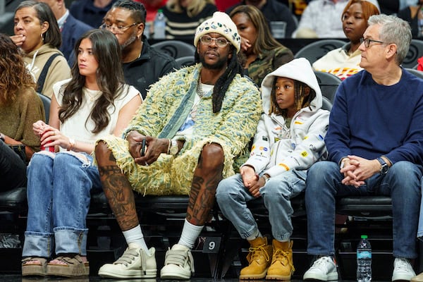 Rapper 2 Chainz and his son sits courtside during the first half of an NBA basketball game between the New York Knicks and Atlanta Hawks, Wednesday, Nov. 6, 2024, in Atlanta. (AP Photo/Jason Allen)