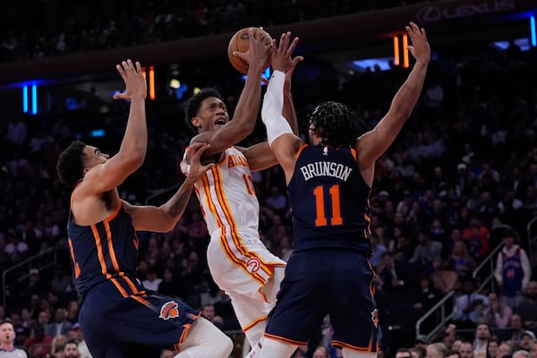 New York Knicks' Karl-Anthony Towns (32) and Jalen Brunson (11) defend Atlanta Hawks' De'Andre Hunter (12) during the first half of an Emirates Cup NBA basketball game Wednesday, Dec. 11, 2024, in New York. (AP Photo/Frank Franklin II)