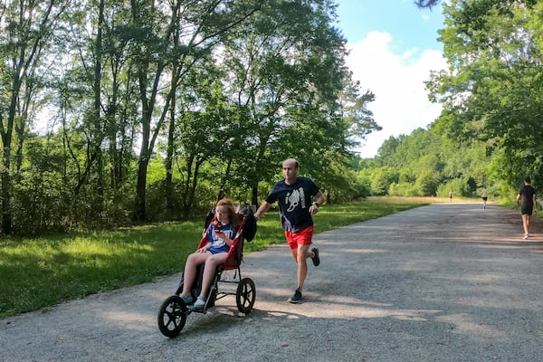 David Glass and his 18-year-old daughter Darden train at the Cochran Shoals Trail along the Chattahoochee River. Glass and Darden, who has Down syndrome, became the first competitive push-assist team to qualify for the AJC Peachtree Road Race on their first attempt, with a time of 43.01. (Jason Getz / Jason.Getz@ajc.com)