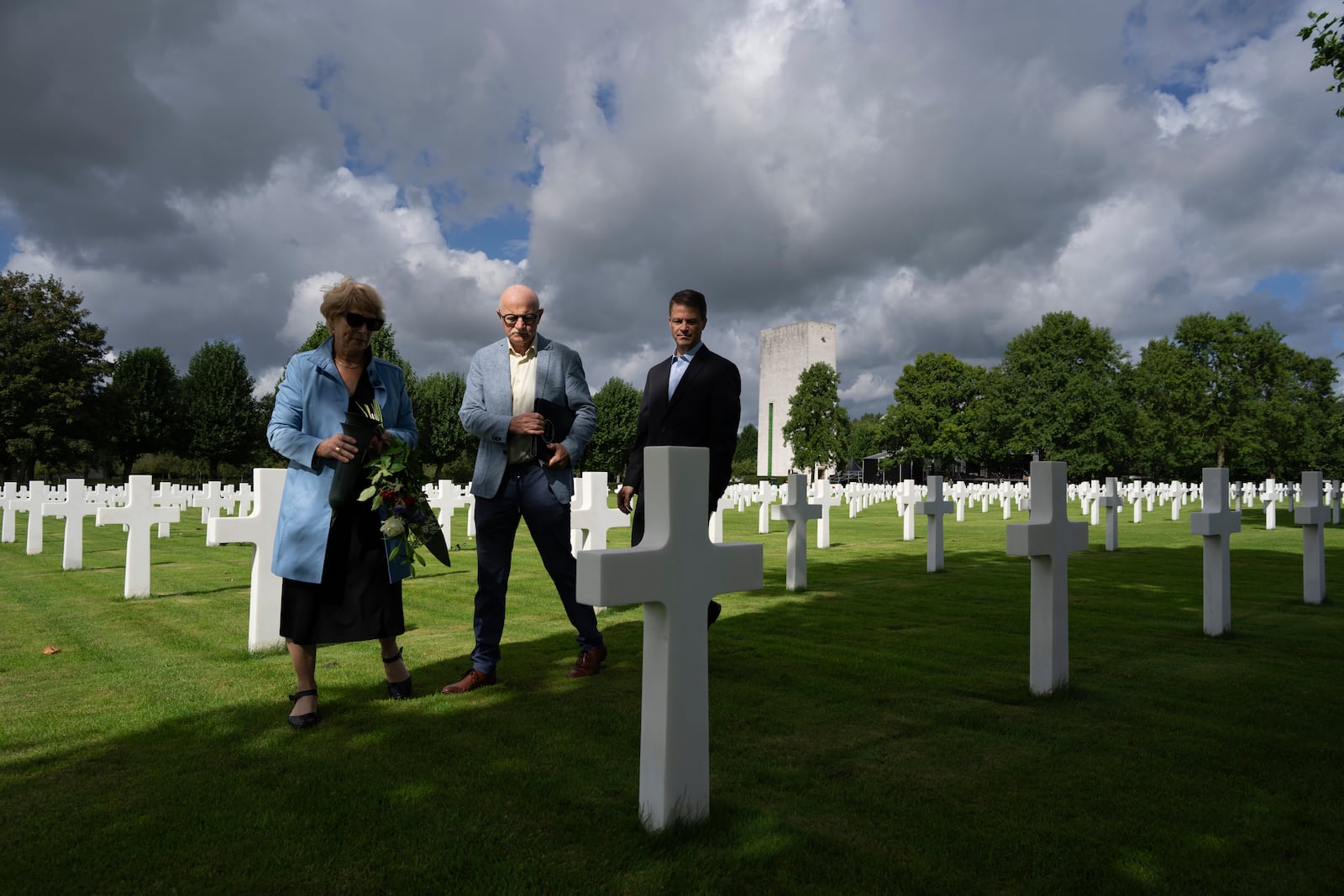 Eighty years after the liberation of the south of the Netherlands, Scott Taylor, right, Ton Hermes, center, and Maria Kleijnen stand next to the grave of Scott's grandfather Second Lt. Royce Taylor, a bombardier with the 527 Bomb Squadron, at the Netherlands American Cemetery in Margraten, southern Netherlands, on Wednesday, Sept. 11, 2024. (AP Photo/Peter Dejong)